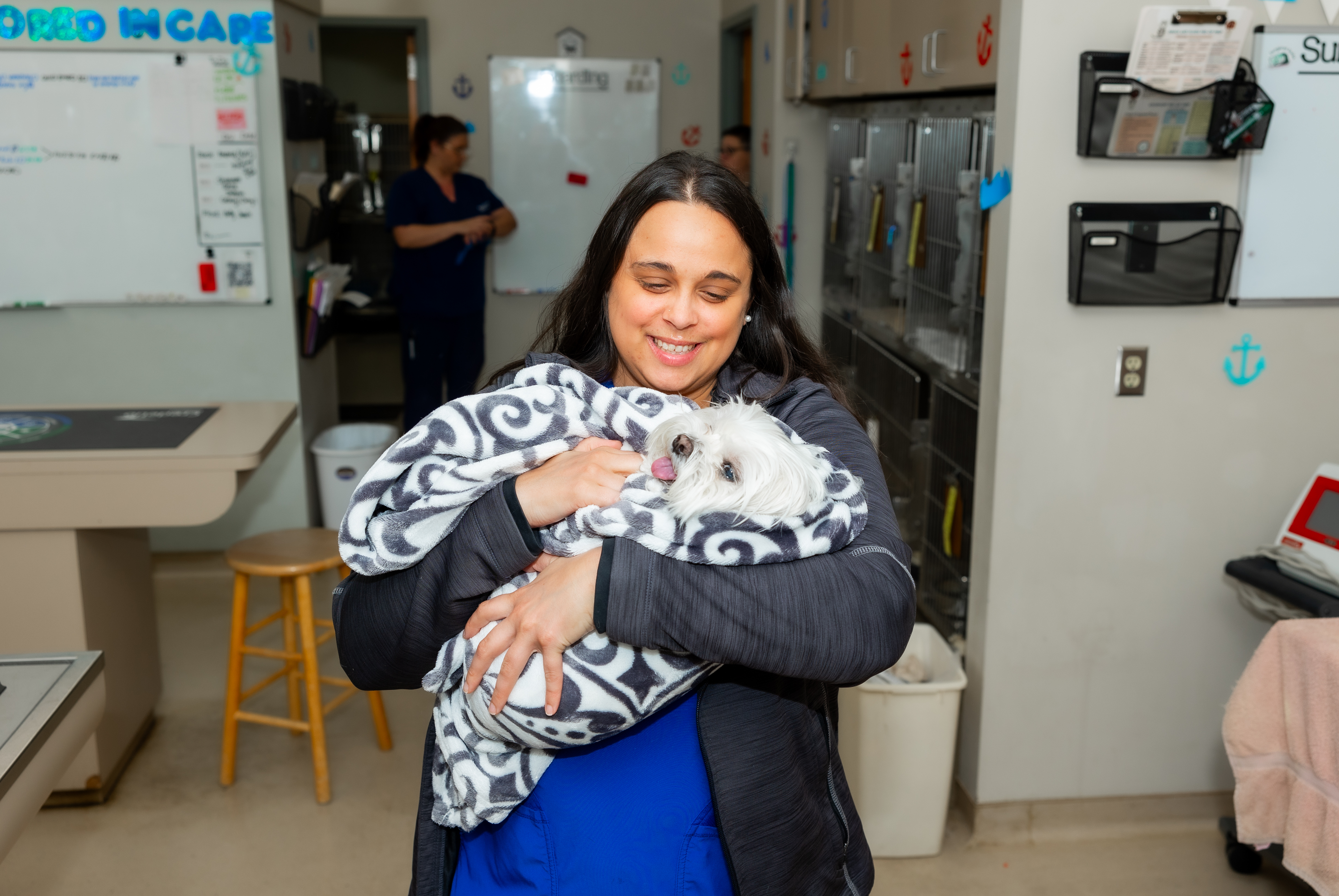 Veterinary technician holding small white dog